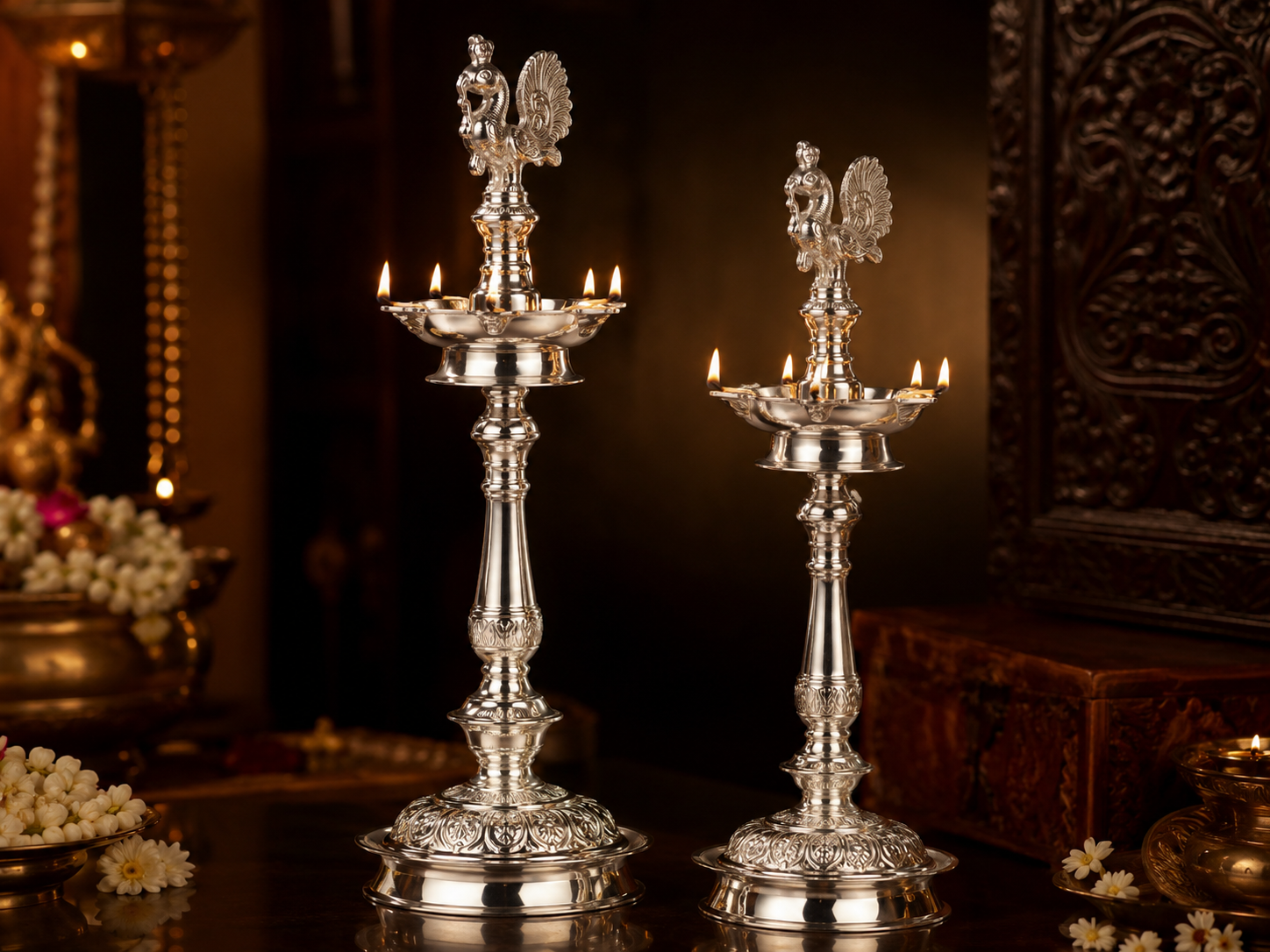Pair of silver peacock oil lamps with lit wicks