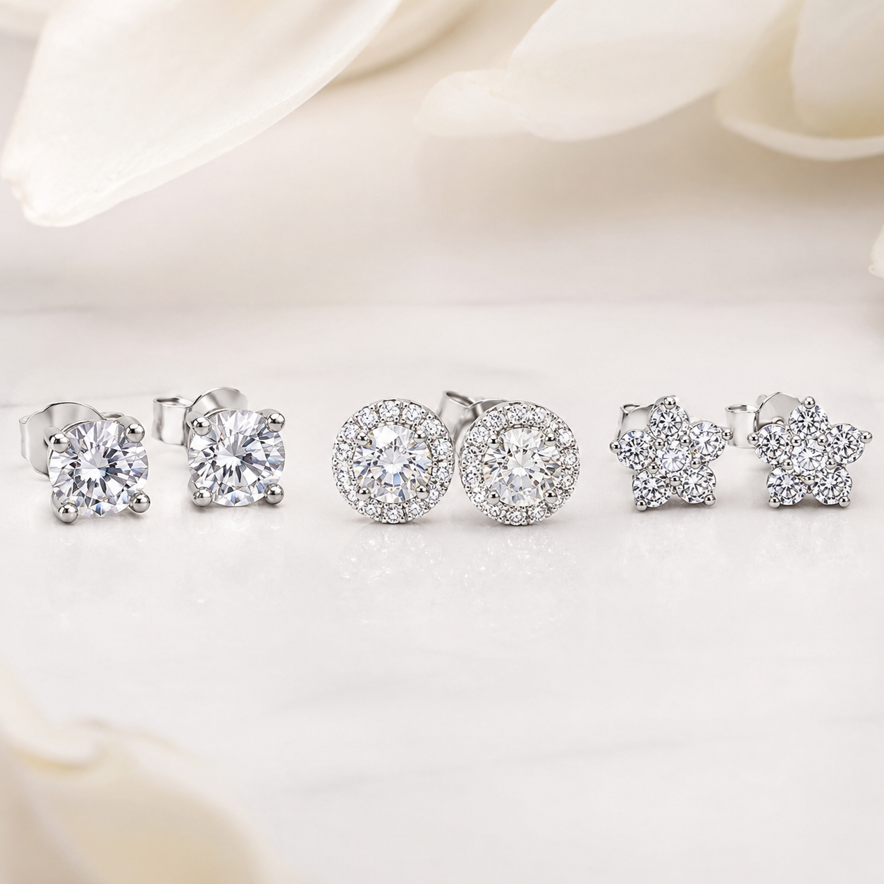 Three pairs of diamond studs on white marble