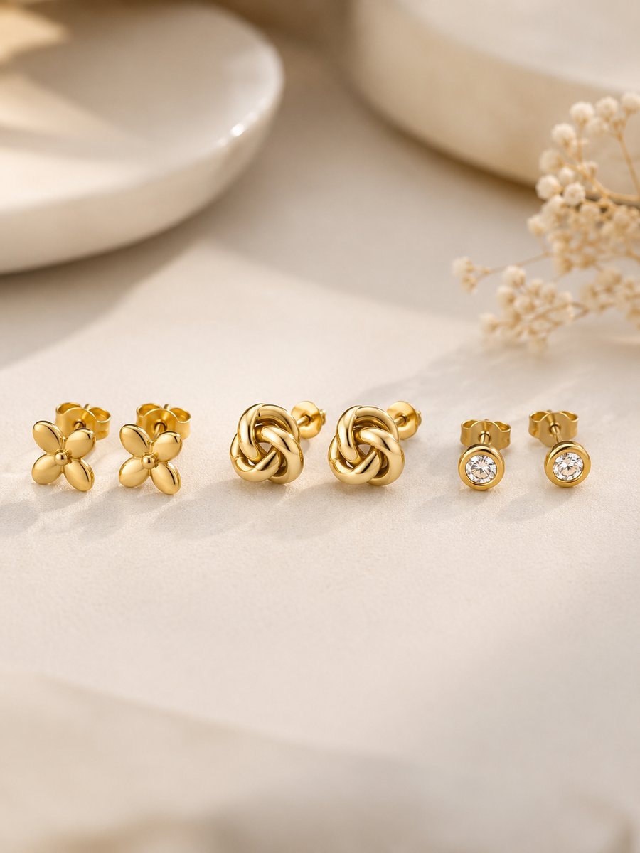 Three pairs of gold stud earrings — flower, knot and stone
