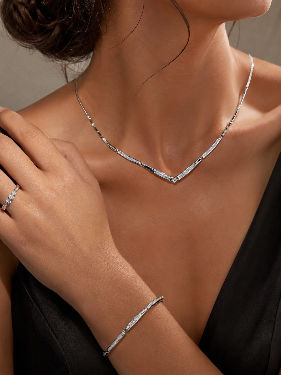Platinum diamond necklace, ring and bracelet worn with a black dress